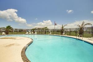 a large blue swimming pool with a fence and palm trees at Walk to Beach Updated Home with Deck in Galveston! in Galveston