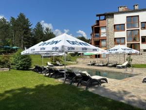 a group of chairs and umbrellas next to a pool at Entire Private Apartment in Pirin Golf & Country Club in Bansko