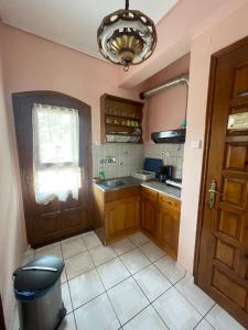 una cocina con armarios de madera y una ventana y una puerta en Diamantoula Rooms, en Kala Nera