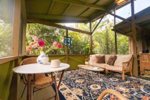 a screened in porch with a table and a couch at Hamakua Sanctuary in Honokaa
