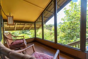 a screened in porch with two chairs and large windows at Hamakua Sanctuary in Honokaa