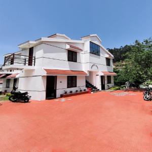 a large white house with a red brick driveway at Ganapathy Garden Homestay in Kodaikānāl
