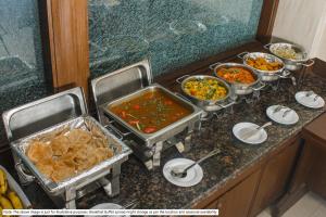 a buffet with many different dishes of food on a counter at Treebo Trend The Appa'S Resort in Mahabaleshwar