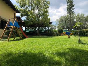 um quintal com um parque infantil com um escorrega e um guarda-chuva em Residenza Giulia em Scanzano Jonico