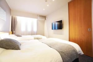 Nishinotōindōri的住宿－Avenir Hotel Kyoto，一间卧室设有三张床,墙上配有电视。