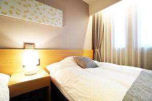 Nishinotōindōri的住宿－Avenir Hotel Kyoto，一间卧室配有一张床和一张桌子上的台灯