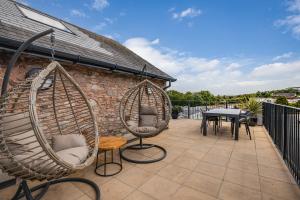 a patio with two hanging chairs and a table at Waterside Apartment in Paignton