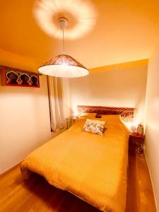 a bedroom with a large yellow bed with a light at Maison de plage à 100m de la mer in Talmont