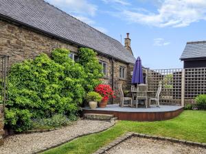 a patio with a table and chairs in a yard at The Old Byre in Upper Hulme