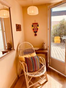 a rattan chair sitting in a room with a window at Maison de plage à 100m de la mer in Talmont
