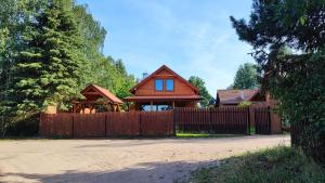 a house with a wooden fence and a gate at Nad Kalwą in Pasym