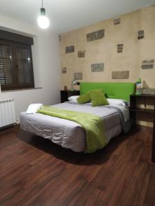 a bedroom with a large bed with a green headboard at La Sabelona 