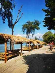 a beach with a fence and people riding a bike at Abdi Fantastik in Gili Islands