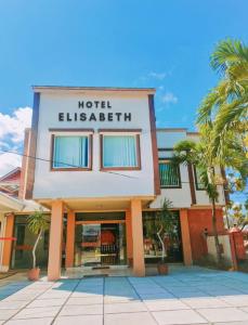 un hotel exterior con palmeras delante en Hotel Elisabeth en Telaga