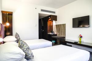 a hotel room with two beds and a flat screen tv at Krishna Palace Hotel in Mumbai