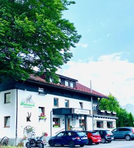 Biały budynek z samochodami zaparkowanymi przed nim w obiekcie Steinbock Bed & Breakfast w mieście Fischen