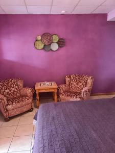 une chambre avec deux chaises et un mur violet dans l'établissement Pension Die kleine Auszeit, à Dénia