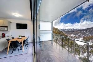 a dining room with a table and chairs and a balcony at Snow Ski Apartments 27 in Falls Creek