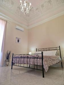 een bed in een witte kamer met een kroonluchter bij Antica Dimora Barocca in Acireale