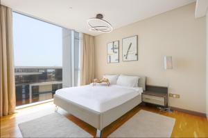 a bedroom with a white bed and a large window at Bluewaters Island - High-Floor 1 Bedroom Suite by Livbnb in Dubai