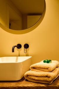 een badkamer met een wastafel, een spiegel en handdoeken bij 't Knus Gewilg in Avelgem
