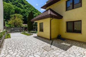 a yellow house with a stone patio in front of it at Cedrus Boutique in Braşov