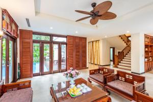 a living room with a ceiling fan and a table and chairs at Luxury Danatrip Villas in Da Nang