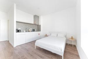 um quarto branco com uma cama branca e uma cozinha em GuestReady - Magnolia Apartments - Studio 2 no Porto