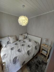 um quarto com uma cama e um lustre em LE PETIT CHALET - Bungalow em Waulsort