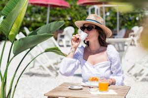 Een vrouw aan een tafel die een kop sinaasappelsap drinkt. bij Hotel Soraya - Spiaggia Sawasdee in Riccione