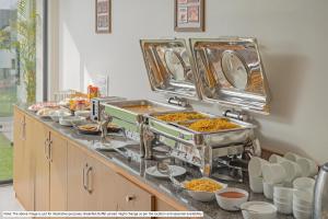 a buffet line with dishes of food on a counter at Treebo Tryst Grand Emerald in Pune