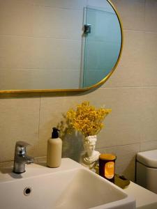a bathroom sink with a mirror and a vase with flowers at EkoCheras Residences Van Gogh theme design with MRT Cheras in Kuala Lumpur