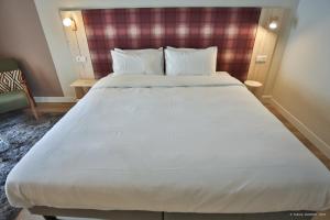 ein großes weißes Bett in einem Hotelzimmer in der Unterkunft Hôtel Le Refuge des Sources in Digne-les-Bains