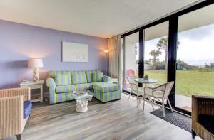 a living room with a couch and a table and chairs at 0102 Beach It by Atlantic Towers in Carolina Beach +13 photos