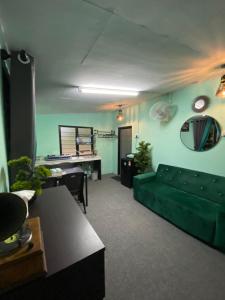 ein Wohnzimmer mit einem grünen Sofa und einem Tisch in der Unterkunft Mini Homestay Arifz Zai in Batu Kurau