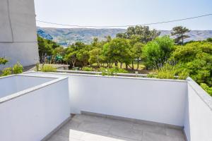 un balcón blanco con vistas a los árboles y a las montañas en Apartment Sidro, en Pag