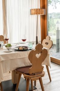 einen Tisch mit einem Teller mit Essen und Gläsern Wein in der Unterkunft Dolmites Nature Hotel Vigilerhof in Seis am Schlern