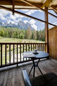 a table on a porch with a view of the mountains at Dolmites Nature Hotel Vigilerhof in Siusi