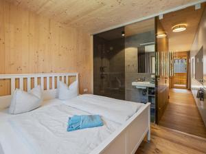 a bedroom with a large white bed and a bathroom at Neues Wood Design Apartment im Herzen des Bregenzerwalds in Mellau