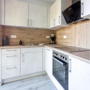 uma cozinha com armários brancos, um lavatório e um fogão em Ferienwohnung Seebär em Wangerland