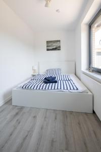 uma cama num quarto branco com piso em madeira em Ferienwohnung Seebär em Wangerland