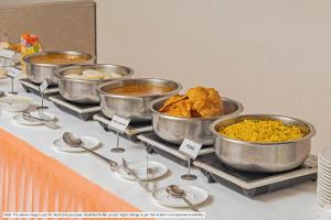 ein Buffet mit mehreren Töpfen voller Speisen auf einem Tisch in der Unterkunft Treebo Premium Arista in Chandīgarh
