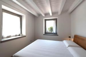 a white bedroom with two windows and a bed at Absentia 1763 Garda Boutique Home in Brenzone sul Garda