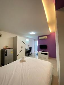 um quarto com uma cama branca e uma parede roxa em PDA Lord Hotel em Bangkok