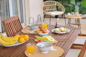 una mesa de madera con platos de fruta y bebidas. en Πολυτελές διαμέρισμα-Πασαλιμάνι, en Pireo