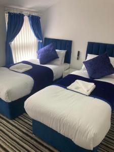 drie bedden in een kamer met blauw en wit bij The New Astoria Hotel in Blackpool