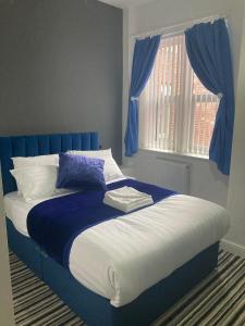 a blue and white bed in a bedroom with a window at The New Astoria Hotel in Blackpool