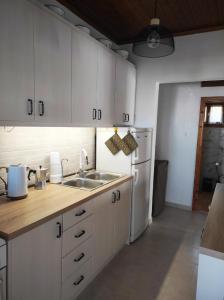 a kitchen with white cabinets and a sink and a refrigerator at Τα πλατάνια 