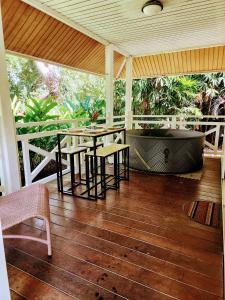 eine Veranda mit einem Tisch, Stühlen und einer Badewanne in der Unterkunft EVASION Bungalow Tropical Spa in Sarraméa