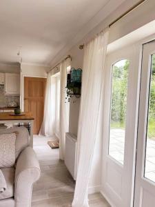 ein Wohnzimmer mit einer Tür mit Vorhängen und einer Küche in der Unterkunft Relaxing retreat near Norfolk Broads in Norwich